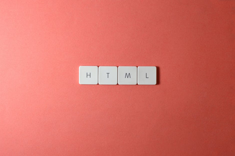 Four white keyboard keycaps spelling out 'HTML' are lined up horizontally on a smooth, pink-colored surface. The keys are evenly spaced, with black letters printed on each, and are illuminated by soft